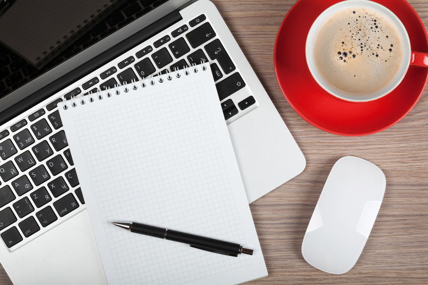 Blank notepad over laptop and coffee cup